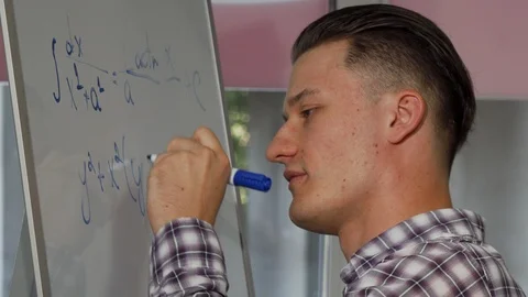 Handsome young man solving math problem on whiteboard Stock Footage 98573627