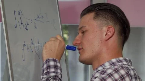 Handsome young man solving math problem on whiteboard Foto stock