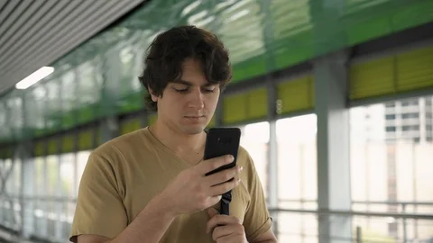 Handsome young man standing and looking at his smartphone screen 스톡 동영상 99366655