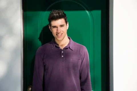 Handsome young man standing in front of house door Stock Photos