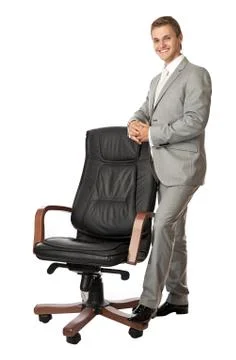 Handsome young man standing next to an armchair Stock Photos