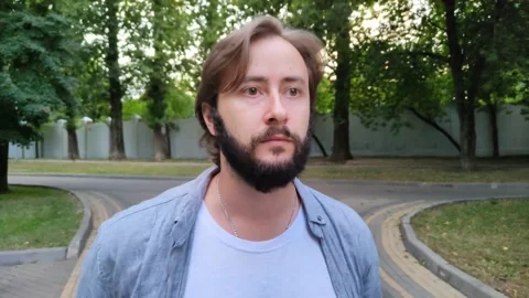 Handsome young man strolls through city public park Stock Footage 208909656