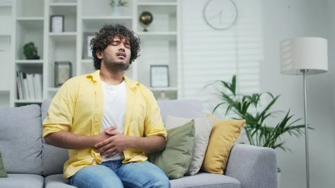 A handsome young man suffers from abdominal pain sudden ache poisoning diarrhea  Stock Footage 235487519