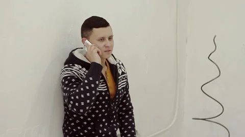 Handsome young man in a sweater talking on the phone Stock Footage 56432758