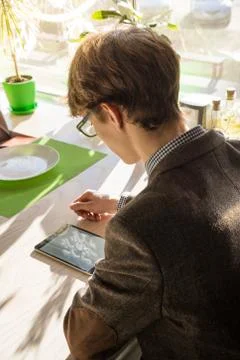 Handsome young man with tablet pc at cafe. Male teenager in tweed jaclet and  Stock Photos
