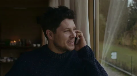 Handsome young man talking on mobile phone and smiling. Stockbeeldmateriaal 56318380