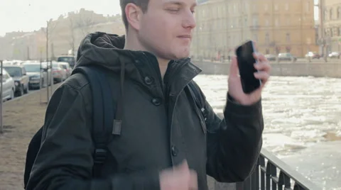 Handsome young man talking on a mobile cell phone on the enbankment Video stock 61867860