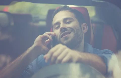 Handsome young man talking on mobile phone while driving his car Stock Photos