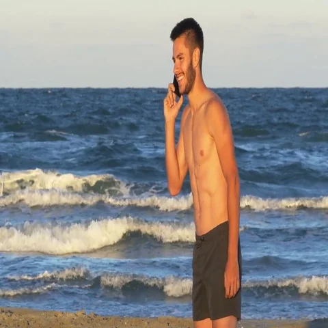 Handsome young man talking on the phone having the sea as background Stock Footage 69699484