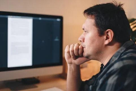 Handsome young man thinking while looking at the computer screen, working fro Stock Photos