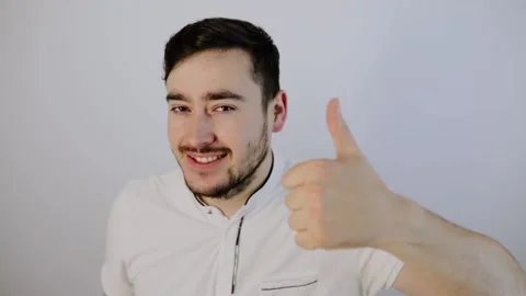 Handsome young man with thumb up, looking at camera Stock Footage 132780301