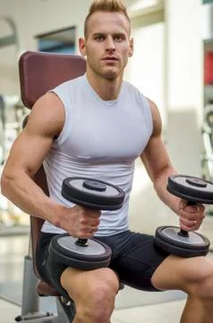Handsome young man training biceps in gym Stock Photos