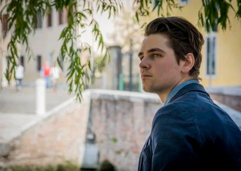 Handsome young man under a tree in town setting Stock Photos