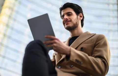 Handsome young man using a digital tablet on a bench outdoor Stock Photos