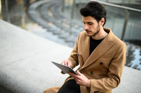 Handsome young man using a digital tablet on a bench outdoor Stock Photos