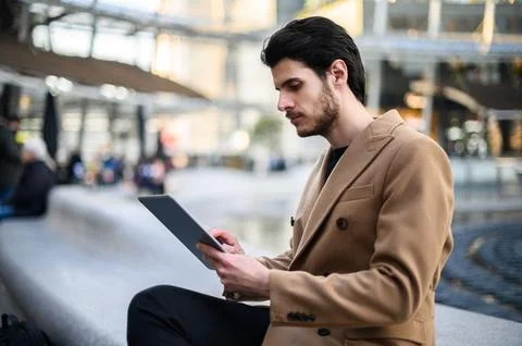 Handsome young man using a digital tablet on a bench outdoor Stock Photos