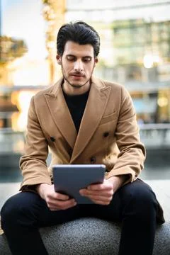 Handsome young man using a digital tablet on a bench outdoor Stock Photos