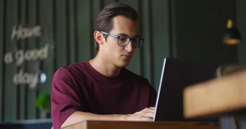 Handsome young man using laptop sitting in cafe. Caucasian male works in coffee Stock Footage 163900634