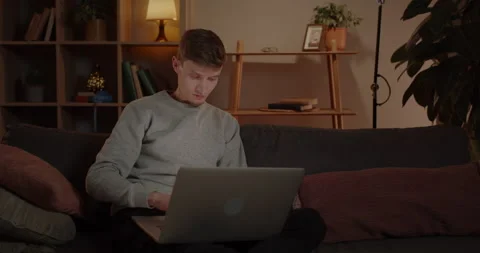 Handsome Young Man Using Laptop While Sitting on Sofa at Home. Male Millennial Stock Footage 234500953