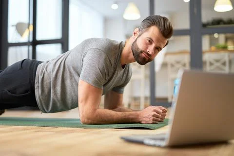 Handsome young man using laptop and doing plank Stock Photos