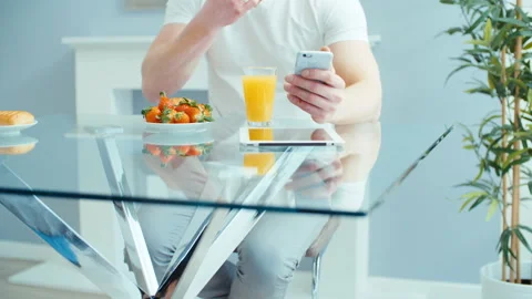 Handsome young man using phone during breakfast. 動画素材 87033374