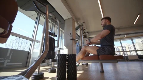 Handsome young man using seated row machine in the gym Video stock 127177559