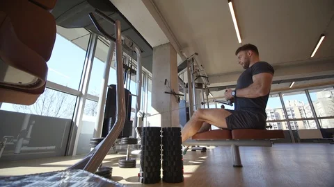 Handsome young man using seated row machine in the gym Video stock 127177729