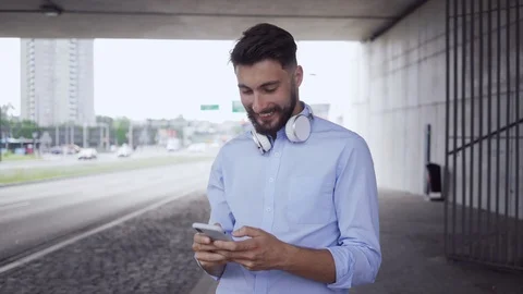 Handsome young man using smartphone while waiting for public transport in the Stock Footage 112869543