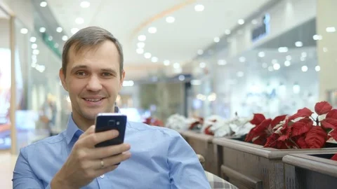 Handsome young man is using smartphone sitting in cafe, smiling. Stock-Footage 125530698