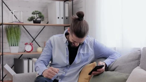 Handsome young man using smartphone and laughing. Happy smiling hipster man with Video stock 164533101