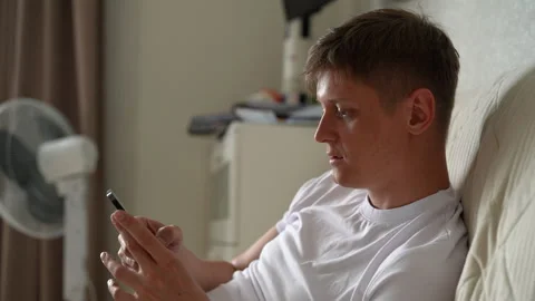 Handsome young man using smartphone while sitting on couch. Happy male using app Video stock 277122482