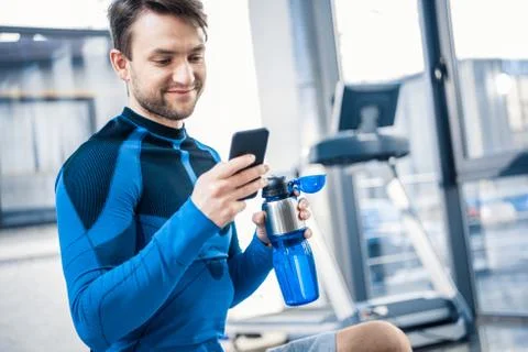 Handsome young man using smartphone at gym 库存照片
