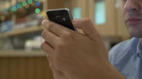 Handsome young man using a smartphone, drinking coffee and smiling while Stock Photos