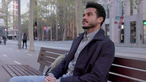 Handsome young man waiting for someone on a city bench Stock Footage 345096267