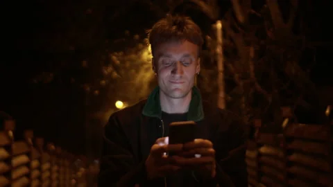 Handsome young man walking and typing text with his smartphone Stock Footage 150688937