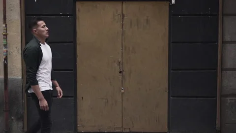 Handsome young man walking down the street in front of a closed door in Madrid Video stock 205306592