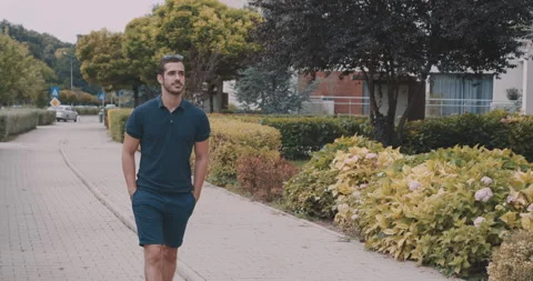 Handsome young man walking outside with his hands in his pockets Stock Footage 132134235