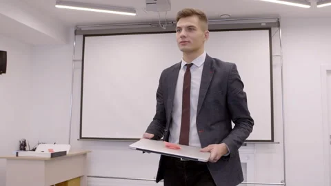 Handsome young man walks through office and joins women at desk with laptop. Stock Footage 85645158