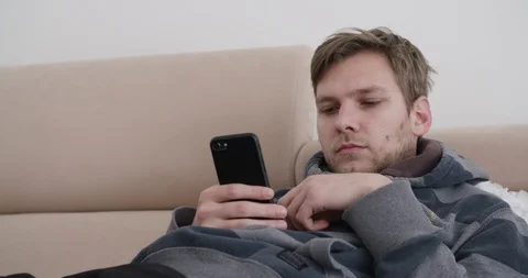 Handsome young man watching smart phone and playing with his fingers  Stock Footage 124105857