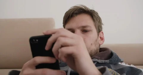 Handsome young man watching smart phone and playing with his fingers  Stock Footage 124105898