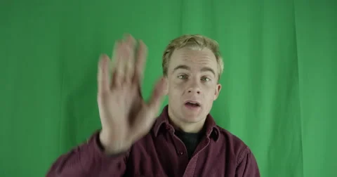 Handsome young man waves to an acquaintance on a greenscreen Vidéo 59725380