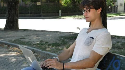 Handsome young man working at computer in park Stock Photos