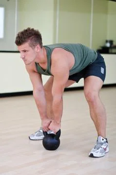 Handsome young man working out in gym with kettlebell Stock Photos