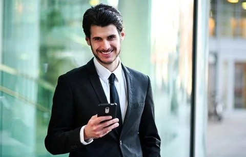 Handsome young manager using a smartphone outdoor Photos