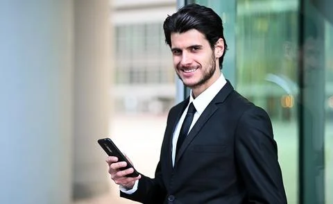 Handsome young manager using a smartphone outdoor Stock Photos