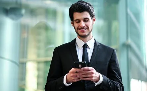 Handsome young manager using a smartphone outdoor Stock-Fotos