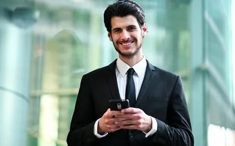 Handsome young manager using a smartphone outdoor Stock Photos