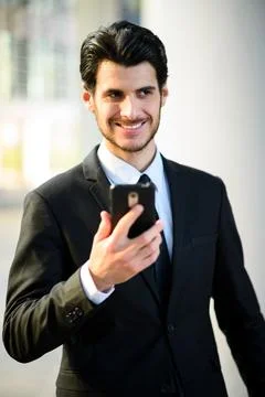 Handsome young manager using a smartphone outdoor Stock Photos