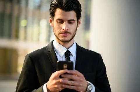 Handsome young manager using a smartphone outdoor Stock Photos