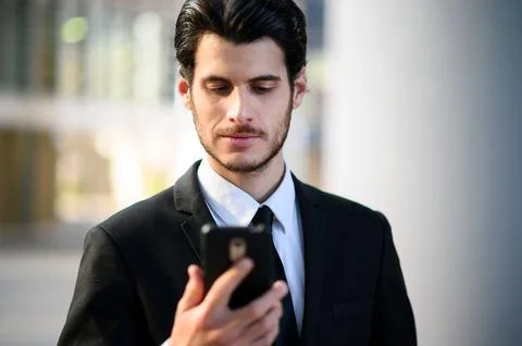 Handsome young manager using a smartphone outdoor Stock Photos